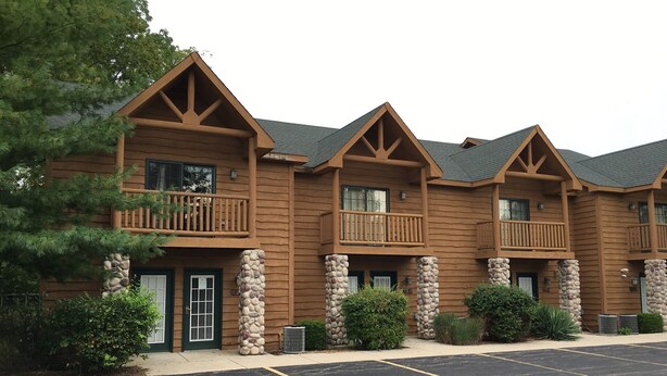 Un chalet à plusieurs étages, doté d’un design rustique, avec des balcons et des piliers en pierre.