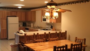 Une cuisine avec des meubles de rangement en bois, un réfrigérateur, une cuisinière et une table à manger avec des chaises.