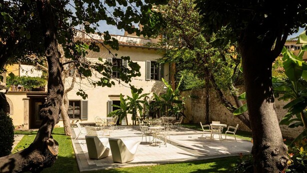 A courtyard with outdoor seating, a building with shutters, and lush greenery. - Numa Florence  Palazzo San Niccolò (Florence)