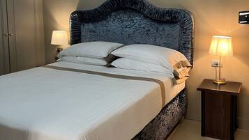 A neatly made bed with white linens and a dark headboard, flanked by two bedside lamps on matching nightstands.