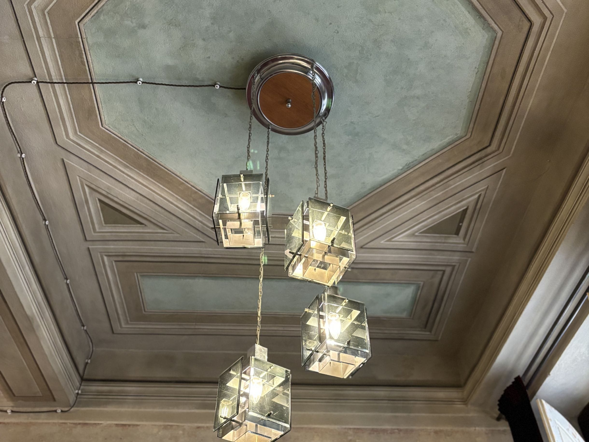 Techo con un diseño geométrico y una lámpara colgante con múltiples cubos de vidrio transparente.