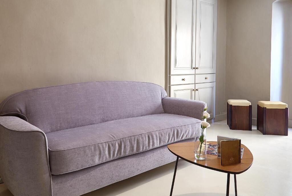 En moderne stue med en grå sofa, et lille træbord og to matchende skamler.