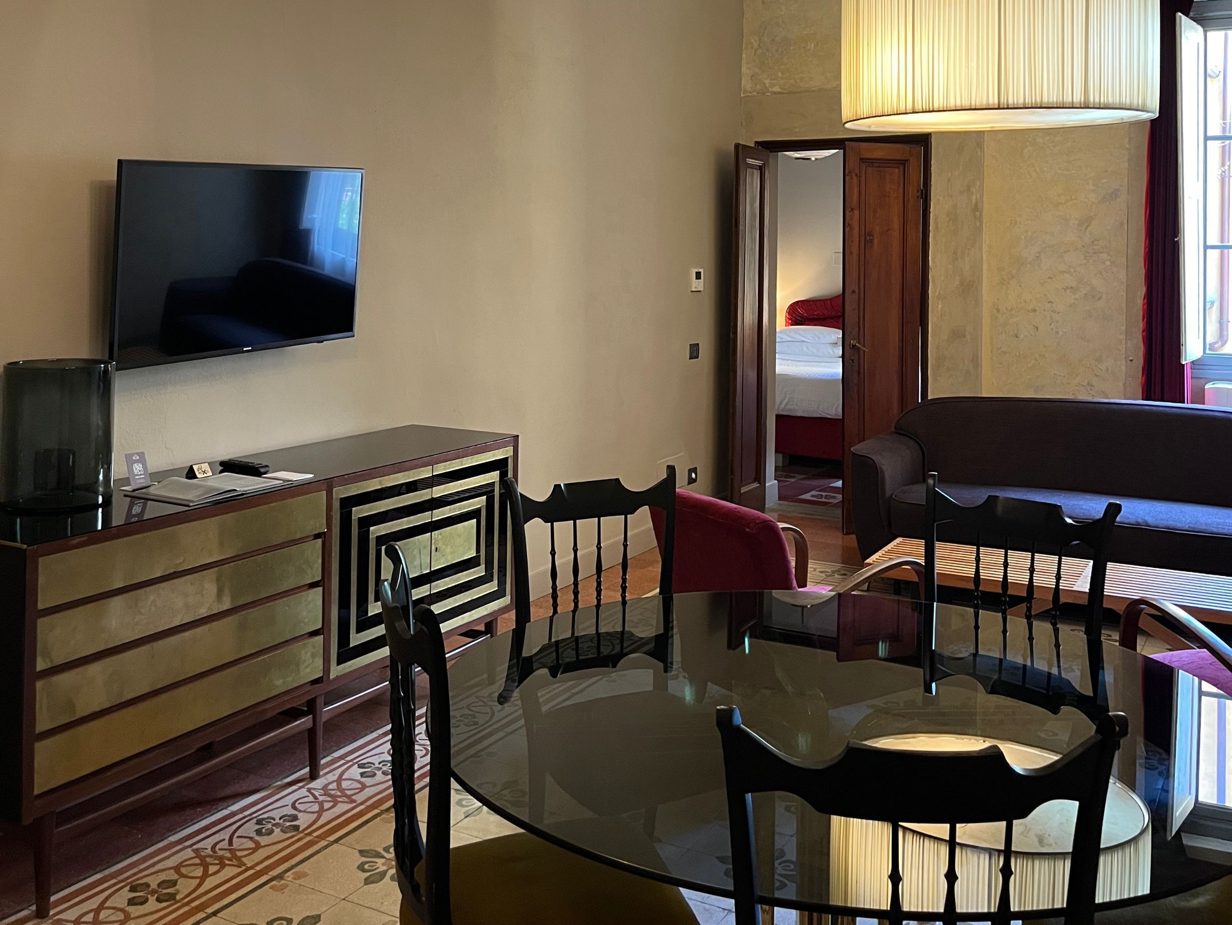 Ein Wohnzimmer mit Fernseher, Esstisch mit Stühlen, einer Couch und einer Lampe.
