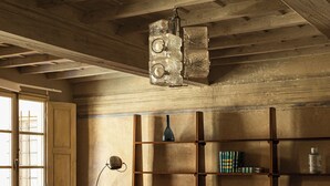 A cozy living room with a wooden ceiling, a bookshelf, a brown armchair, and a sofa. - Numa Florence  Palazzo San Niccolò (Florence)