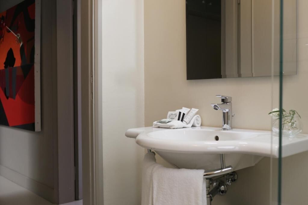 A modern bathroom with a white sink, a mirror, and a glass shower enclosure.