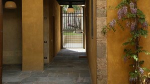 A hallway with a stone floor, a yellow wall, and a gate leading to an outdoor area. - Numa Florence  Palazzo San Niccolò (Florence)