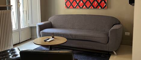 A living room with a grey sofa, a round coffee table, and a black leather chair.