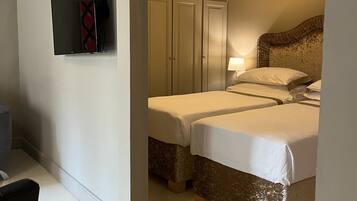 Una camera d'albergo con due letti, un armadio, una televisione e una lampada.
