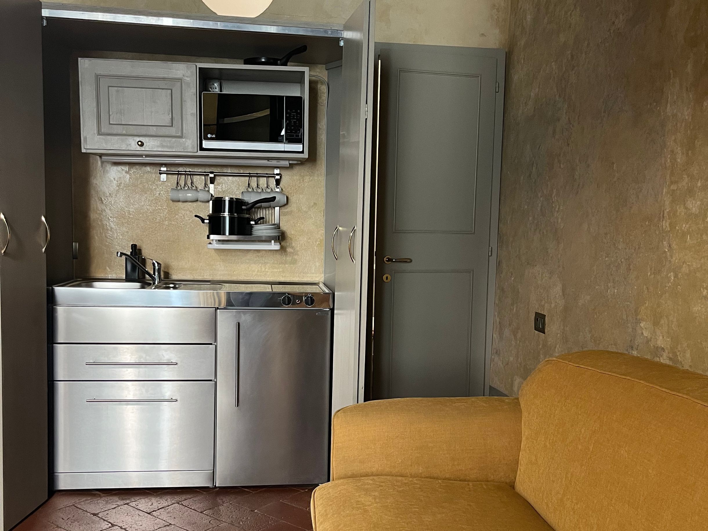 A compact kitchen with stainless steel appliances, a microwave, and a small sink.