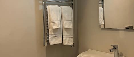 A bathroom with a white sink, a mirror, and a towel rack with two towels.