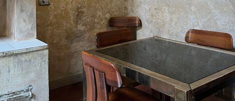A dining table with four wooden chairs, a tiled floor, and a textured wall.