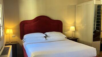 A neatly made bed with white linens, a red headboard, and two bedside lamps.
