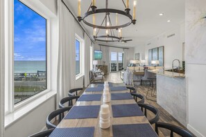 A dining area with a view of the ocean, a chandelier, and a TV in the background. - Crystal View 302 3 Bedrooms | 3 Baths | Accommodates 12 | Pet Friendly (Miramar Beach)