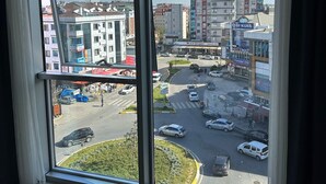 Ein Hotelzimmer mit großem Fenster und Blick auf eine belebte Stadtstraße und Gebäude.