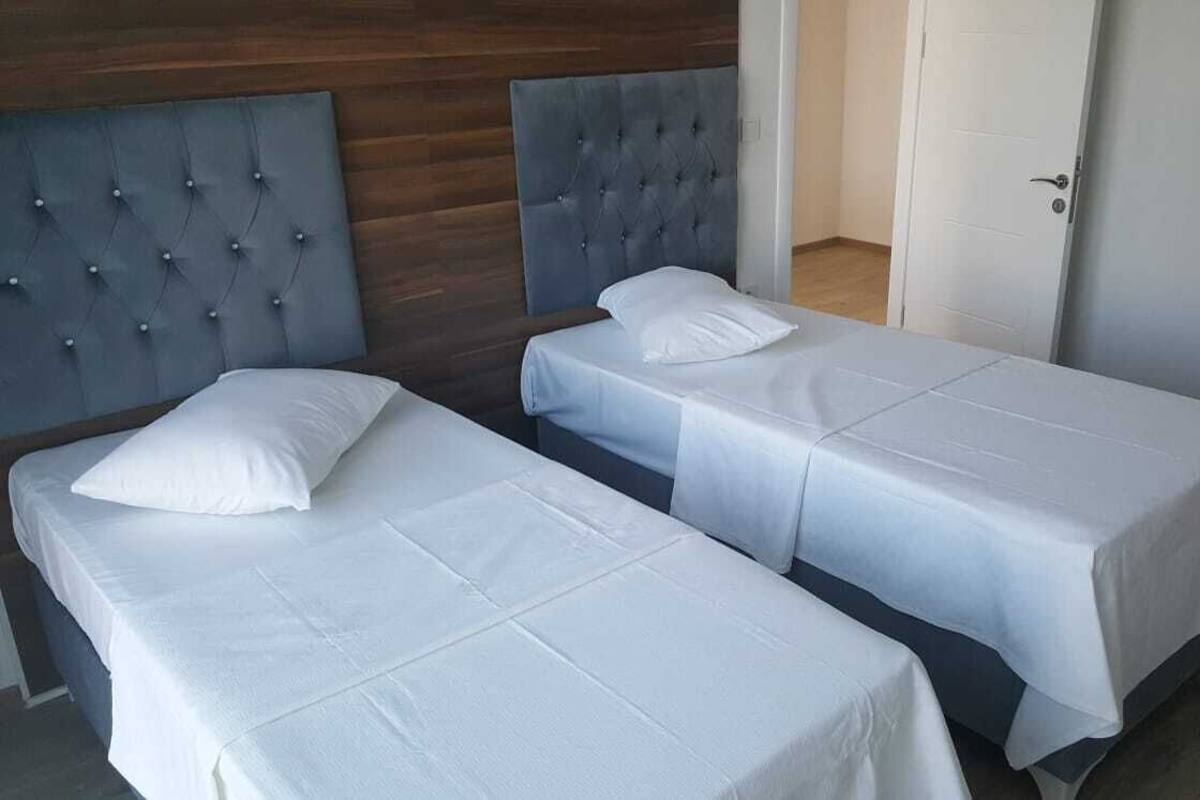 A hotel room with two single beds, each with a headboard and a white bedspread.