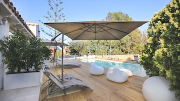 Un pontile in legno con poltrone relax e una piscina.