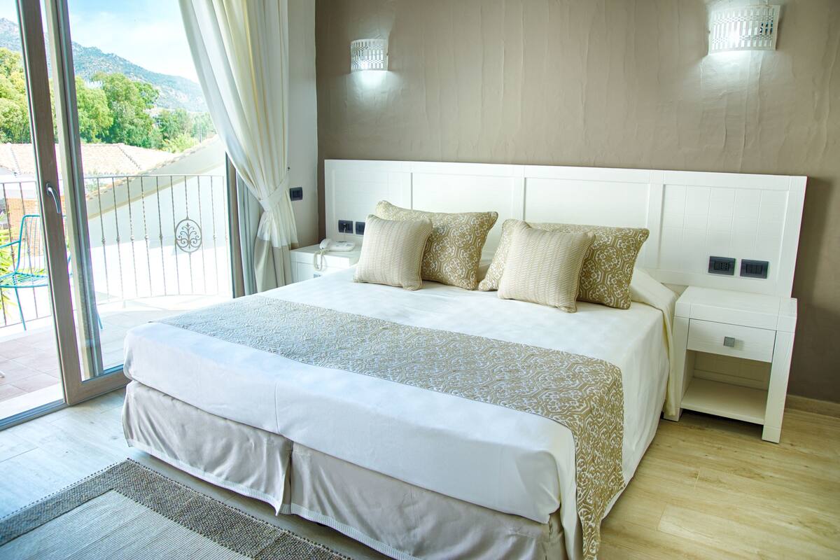 A bedroom with a large bed, white headboard, and bedside tables.