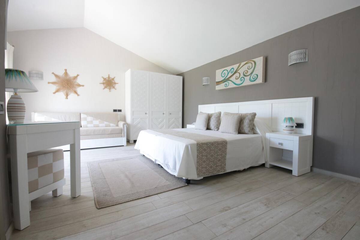 A bedroom with a bed, bedside tables, a desk, and decorative wall art.