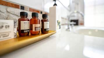 Three bottles of body care products on a wooden shelf in a bathroom.