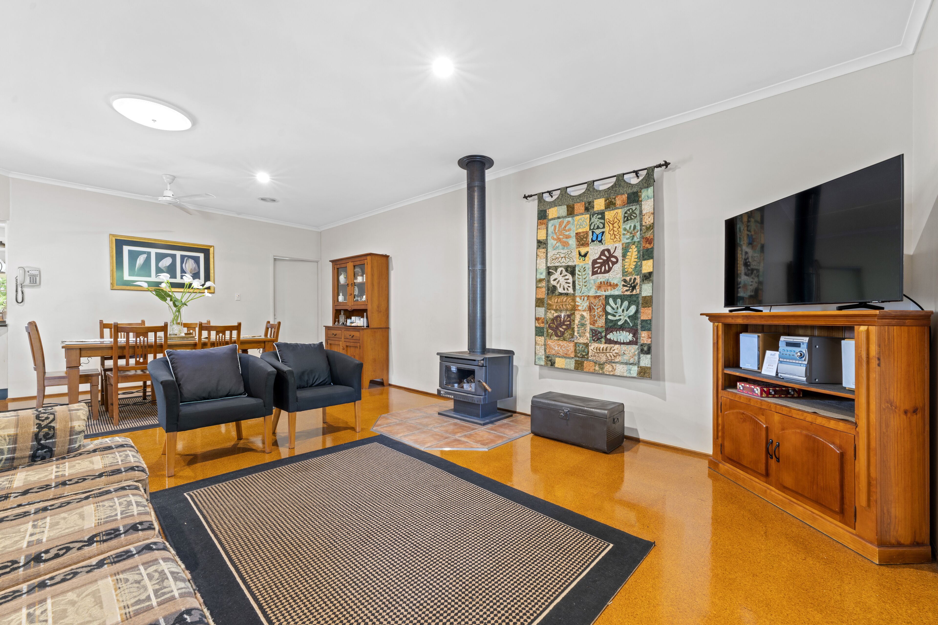 A living room with a sofa, a TV, a fireplace, and a dining area.