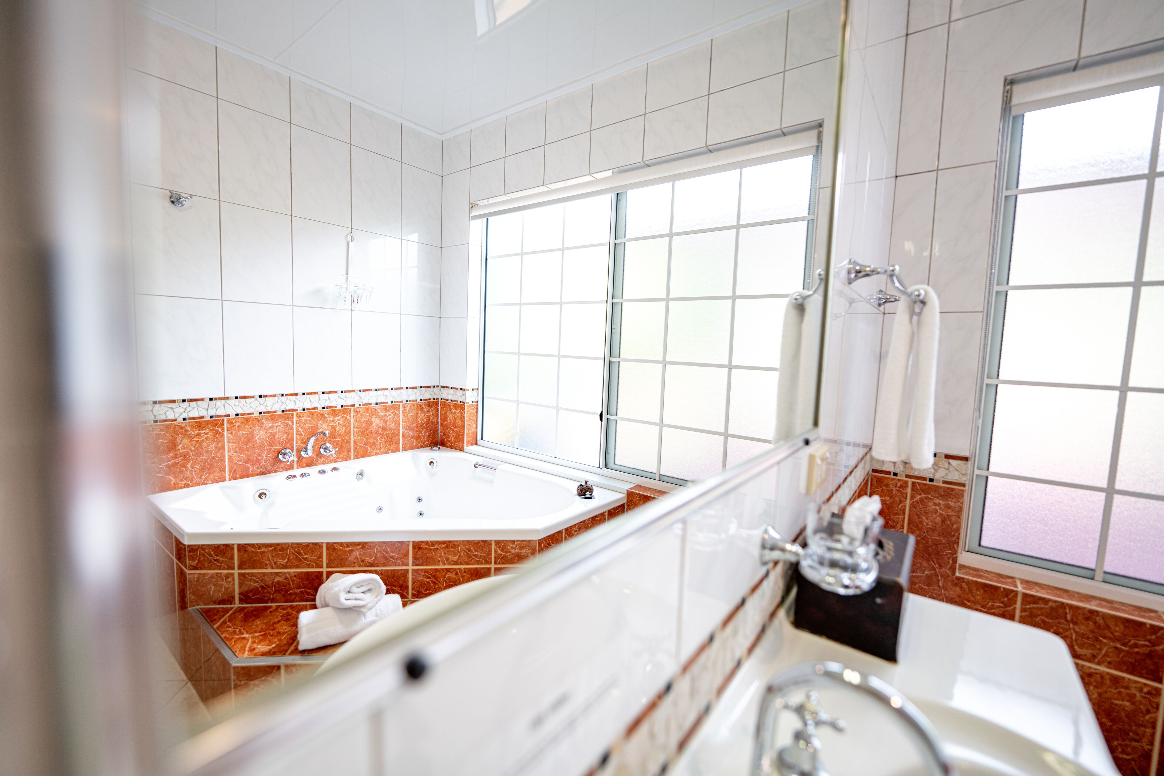 A modern bathroom with a large bathtub, a separate shower area, and a window providing natural light.