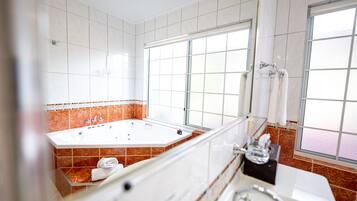 A modern bathroom with a large bathtub, a separate shower area, and a window providing natural light.