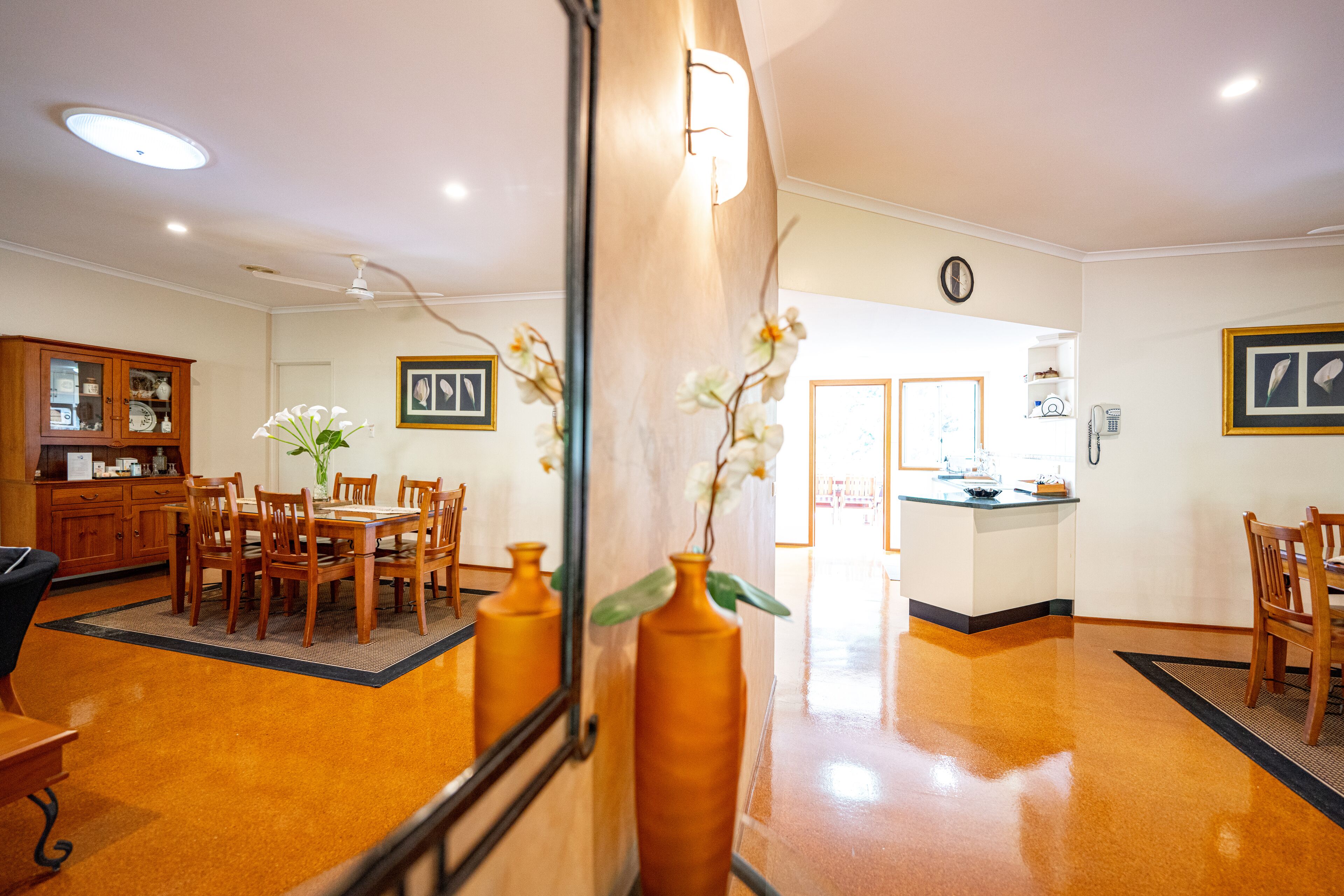 A hotel lobby with a dining area, a reception desk, and a kitchen in the background.