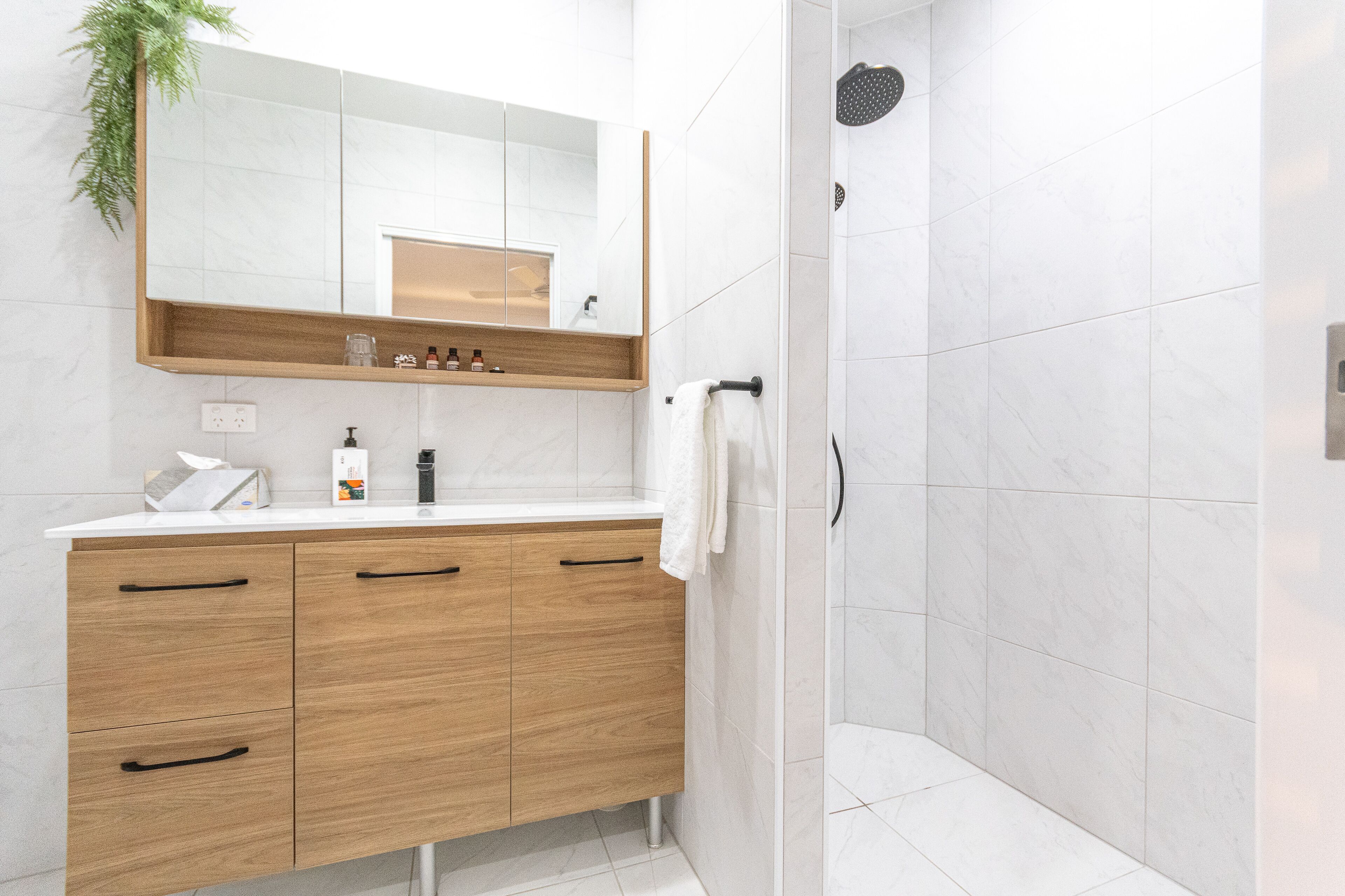 Une salle de bain moderne avec un meuble-lavabo en bois, un grand miroir et un espace douche.