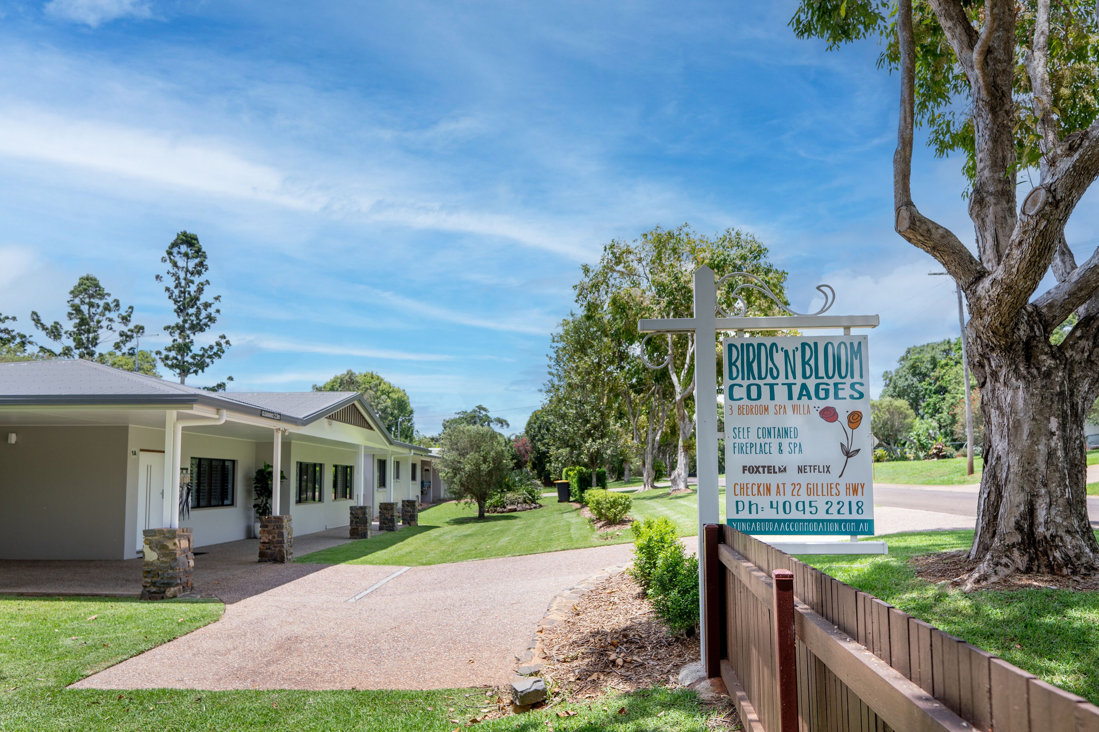 A sign for Birds 'n' Bloom Cottages advertising a self-contained bedroom, spa, and fireplace.