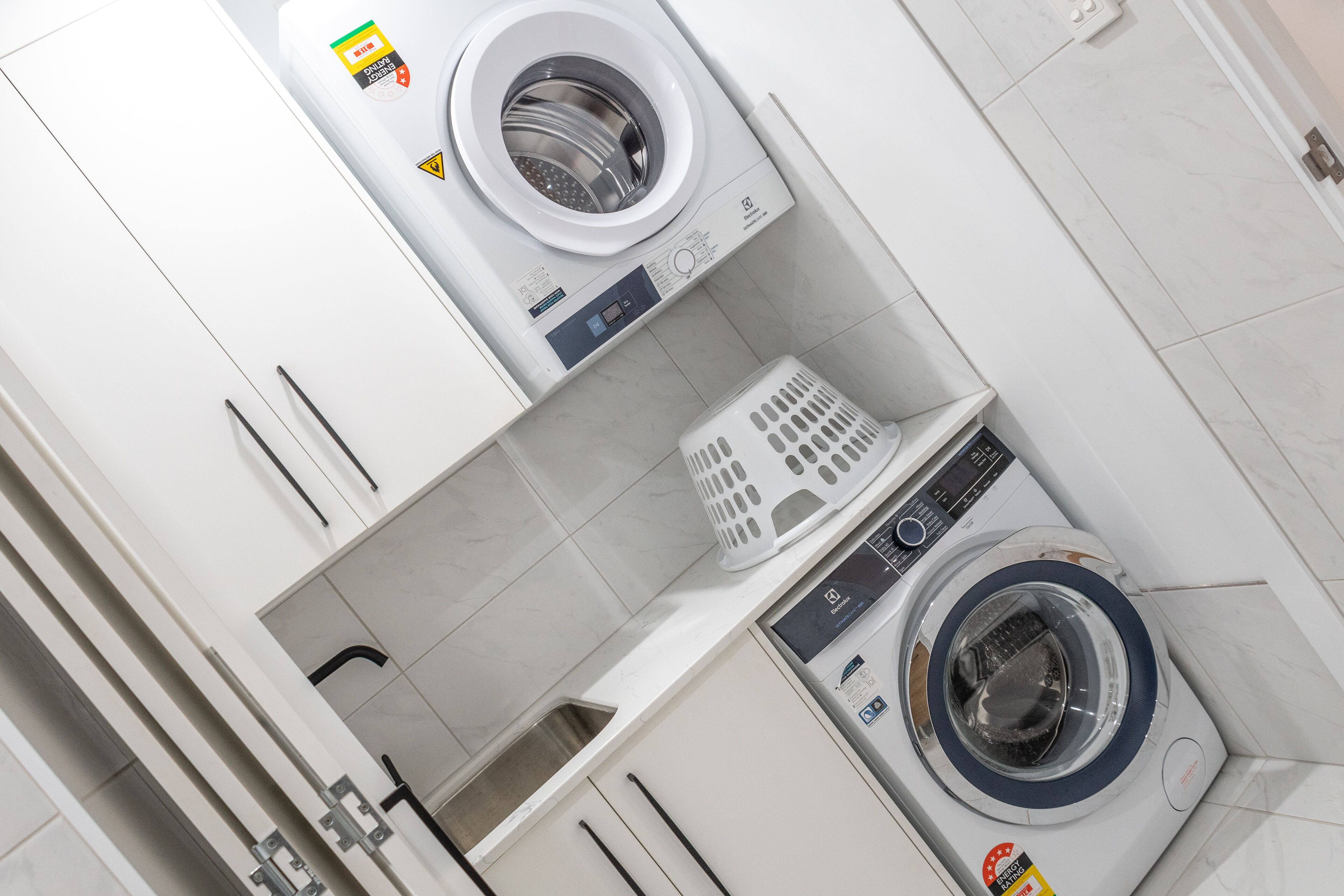 Une buanderie équipée de deux machines à laver, d’un sèche-linge et d’un panier à linge.
