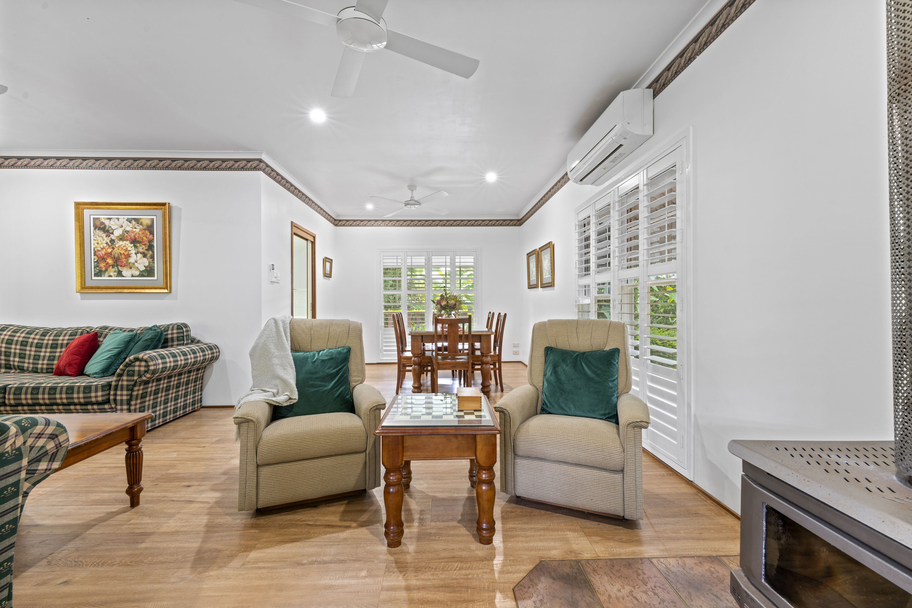 A spacious living room with a wooden coffee table, two armchairs, a sofa, and a fireplace.