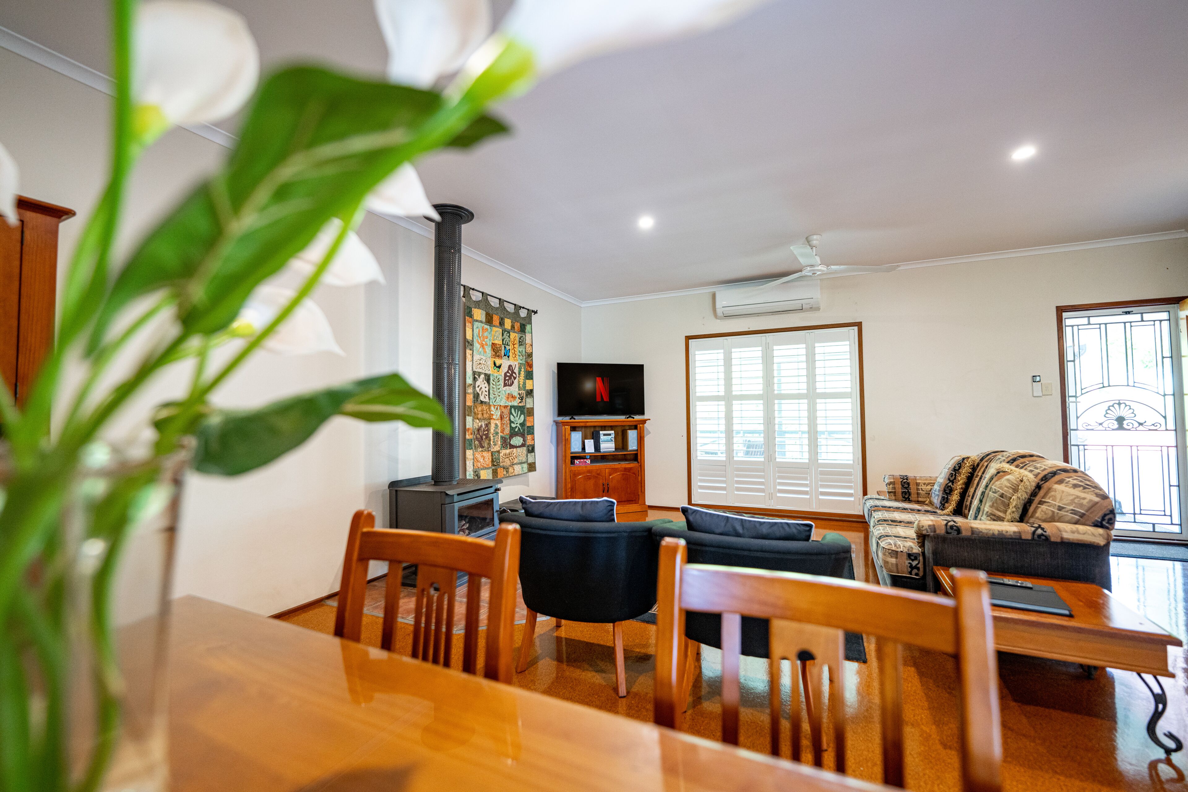A living room with a wooden dining table, two sofas, a TV, and a bookshelf.