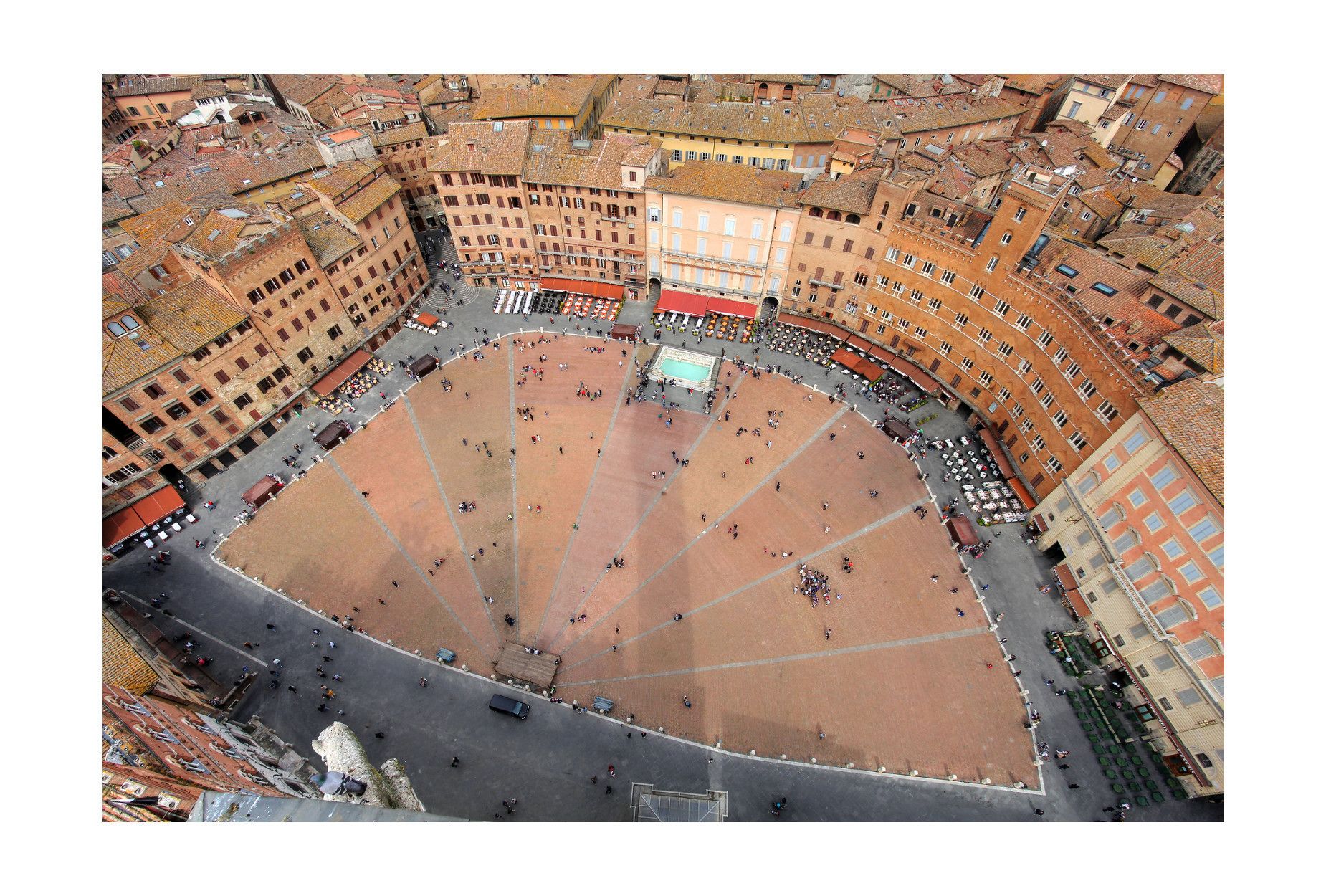 An aerial view of a large, open square surrounded by historic buildings with terracotta roofs.
