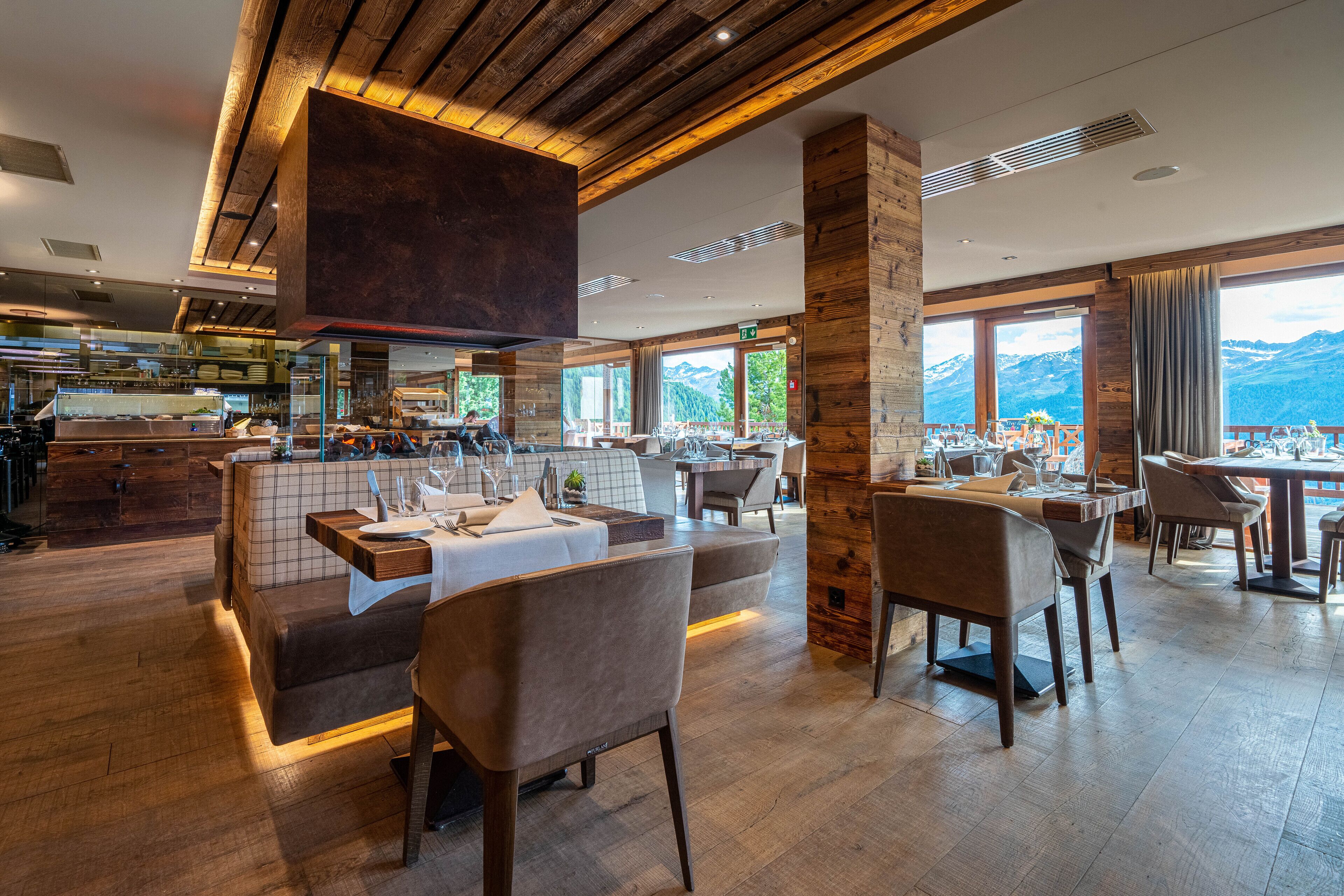 A restaurant with a wooden interior, large windows, and a view of mountains.