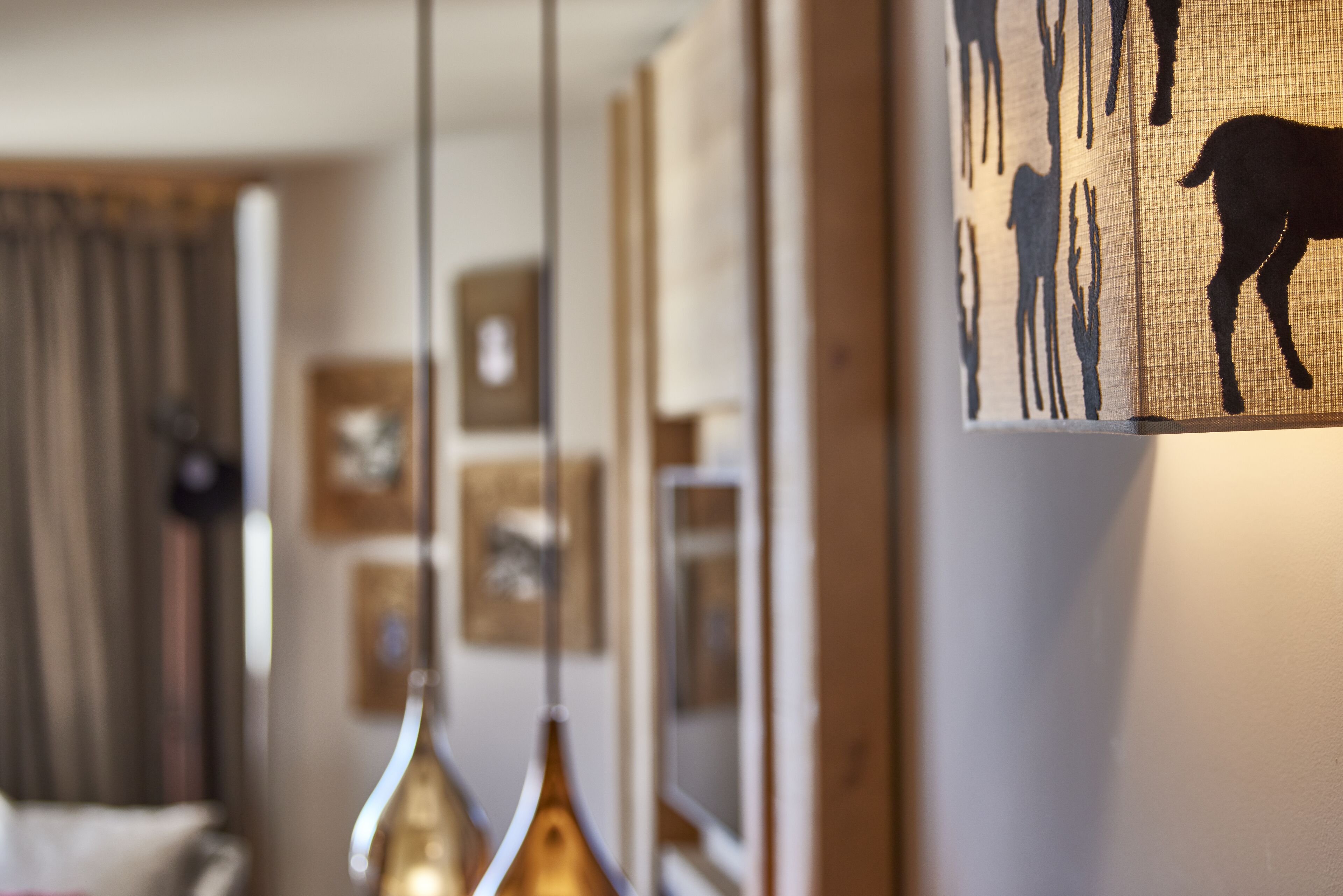 Una habitación con una lámpara colgante, una obra de arte enmarcada en la pared y un ventanal con cortinas.