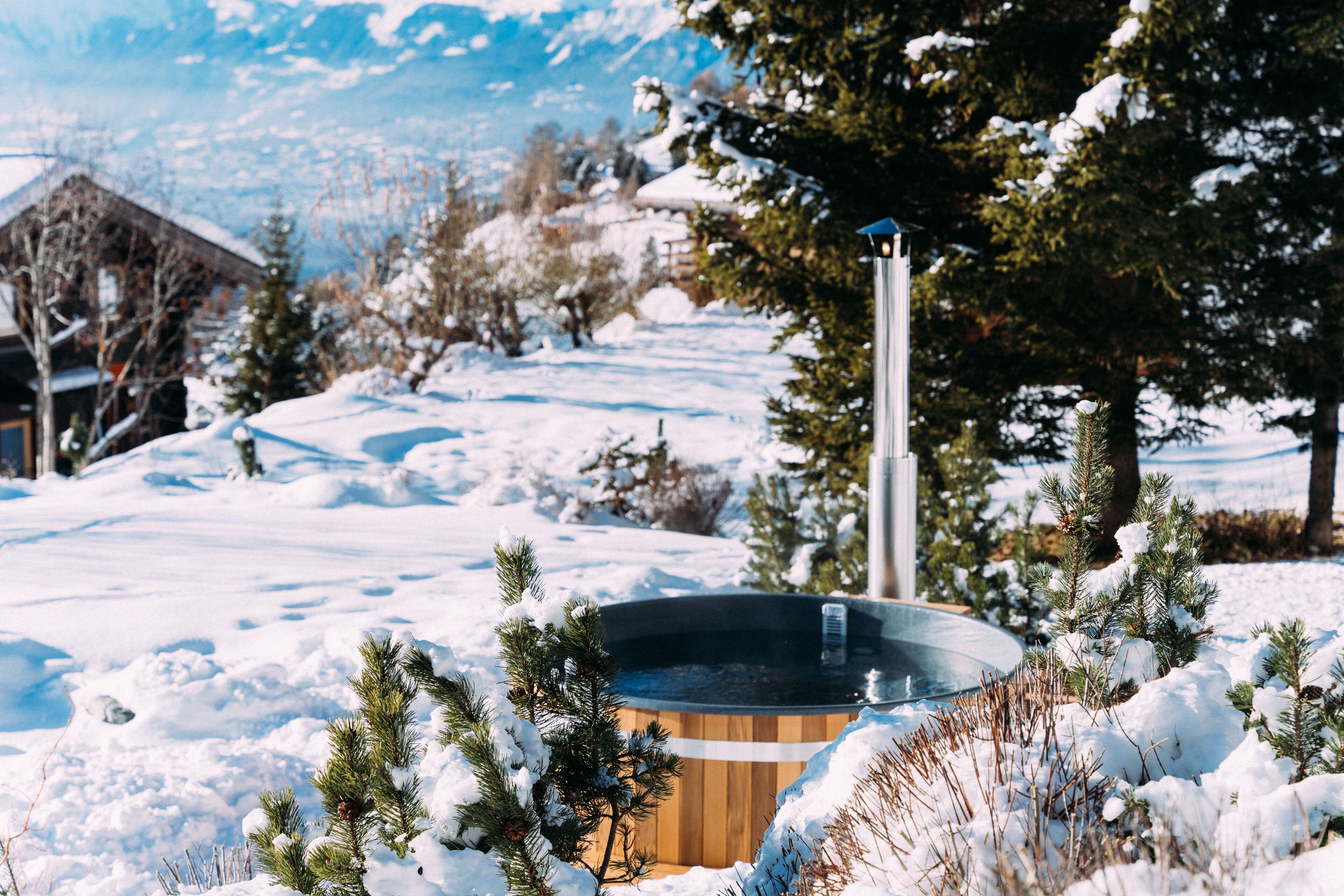 Ein Holzbott im Schnee, umgeben von Bäumen, mit einem Berg im Hintergrund.