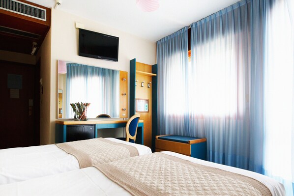 Habitación de hotel con dos camas, un escritorio, televisor y baño.