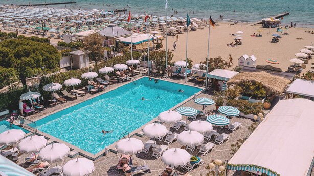 A resort with a swimming pool, beach umbrellas, and lounge chairs. - Hotel Monaco & Quisisana (Jesolo)