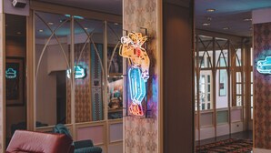A lobby with a red leather sofa, a neon sign, and a patterned wall. - Hotel Monaco & Quisisana (Jesolo)