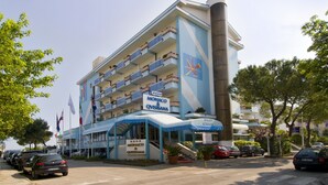 A hotel with a blue and white facade, multiple balconies, and a sign indicating it is the Monaco & Quisiana hotel. - Hotel Monaco & Quisisana (Jesolo)