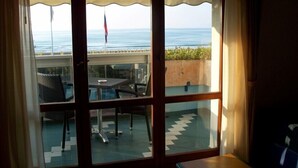 A balcony with a view of the ocean, a flag, and outdoor furniture. - Hotel Monaco & Quisisana (Jesolo)