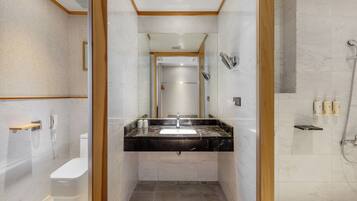 Un baño moderno con tocador de mármol, inodoro, ducha y espejo.