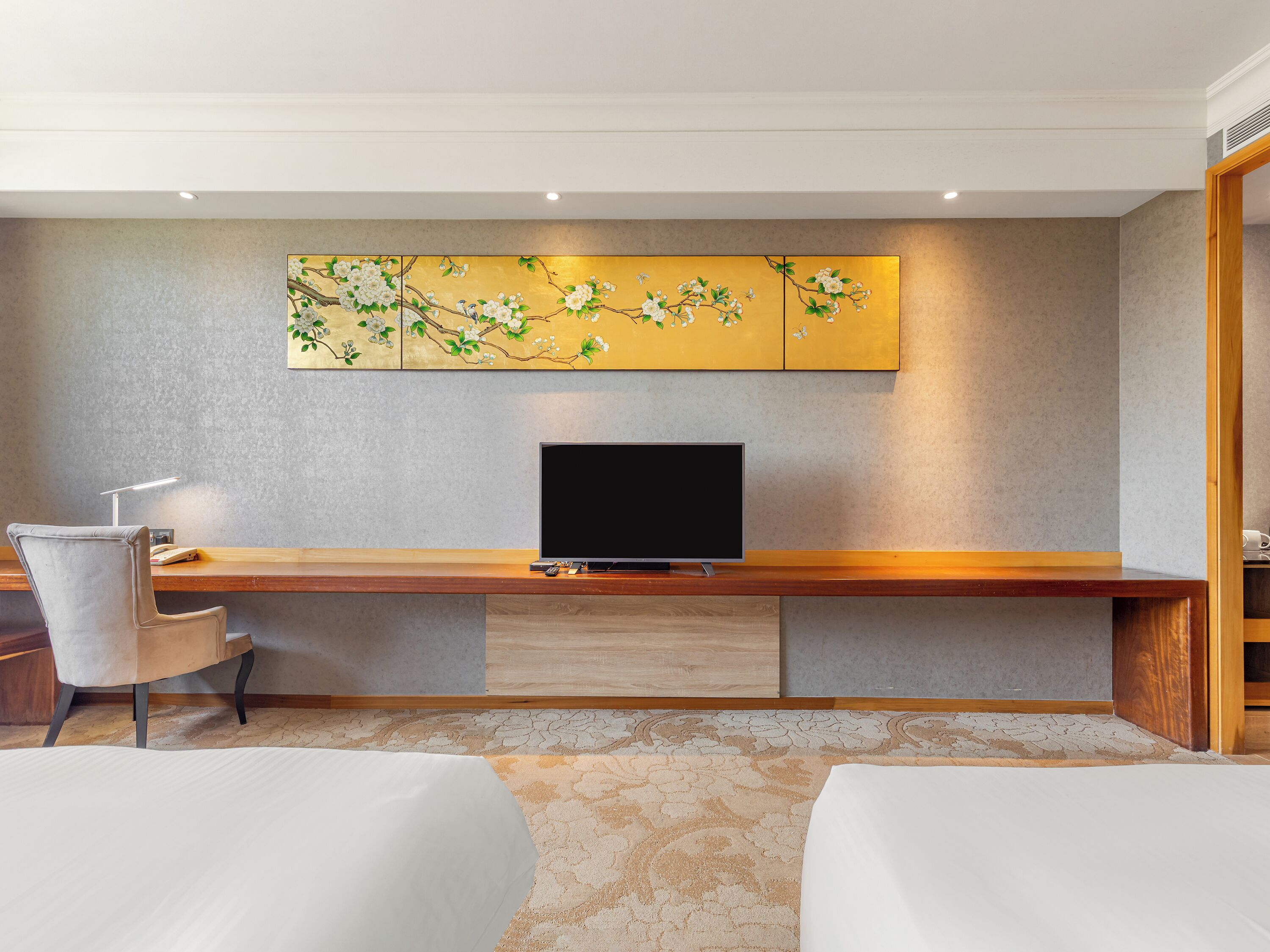 Habitación de hotel con escritorio de madera, televisión de pantalla plana, una silla y una cama.
