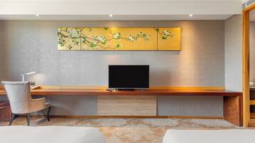 Habitación de hotel con escritorio de madera, televisión de pantalla plana, una silla y una cama.