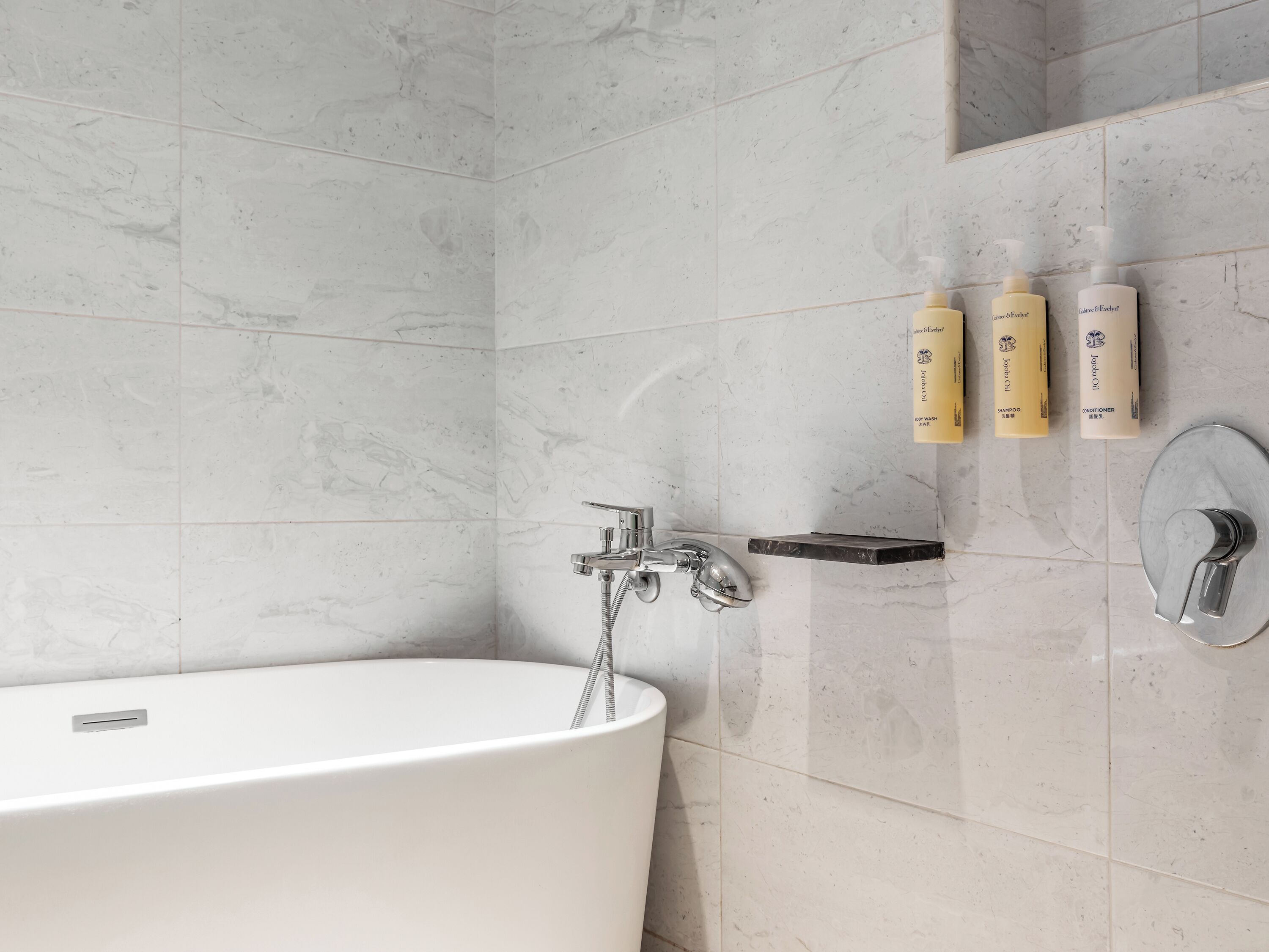 Une salle de bain moderne avec une baignoire sur pieds, une pomme de douche et une étagère pour ranger les articles de toilette.