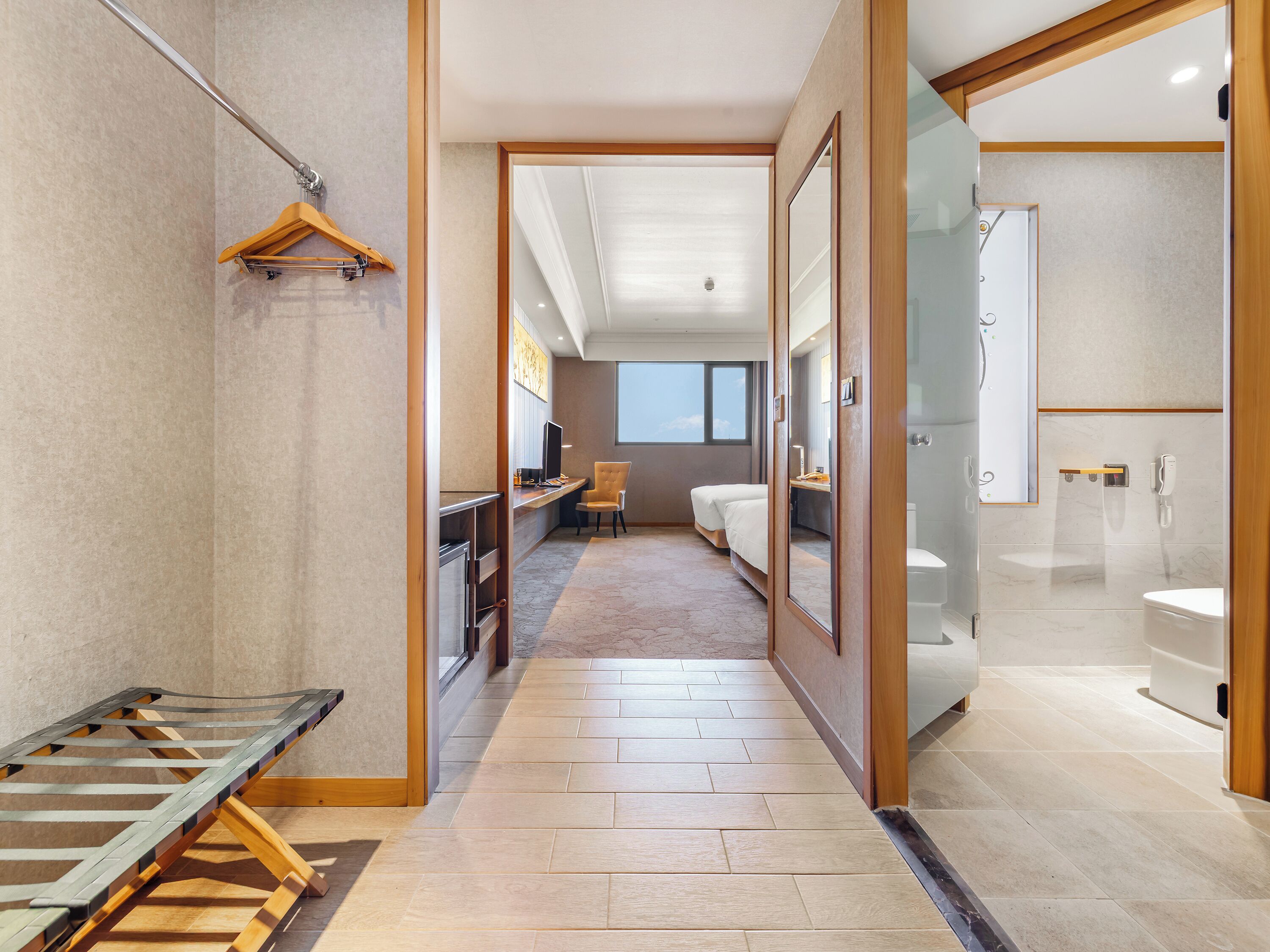 A hotel room with a bed, desk, chair, and a shower area.