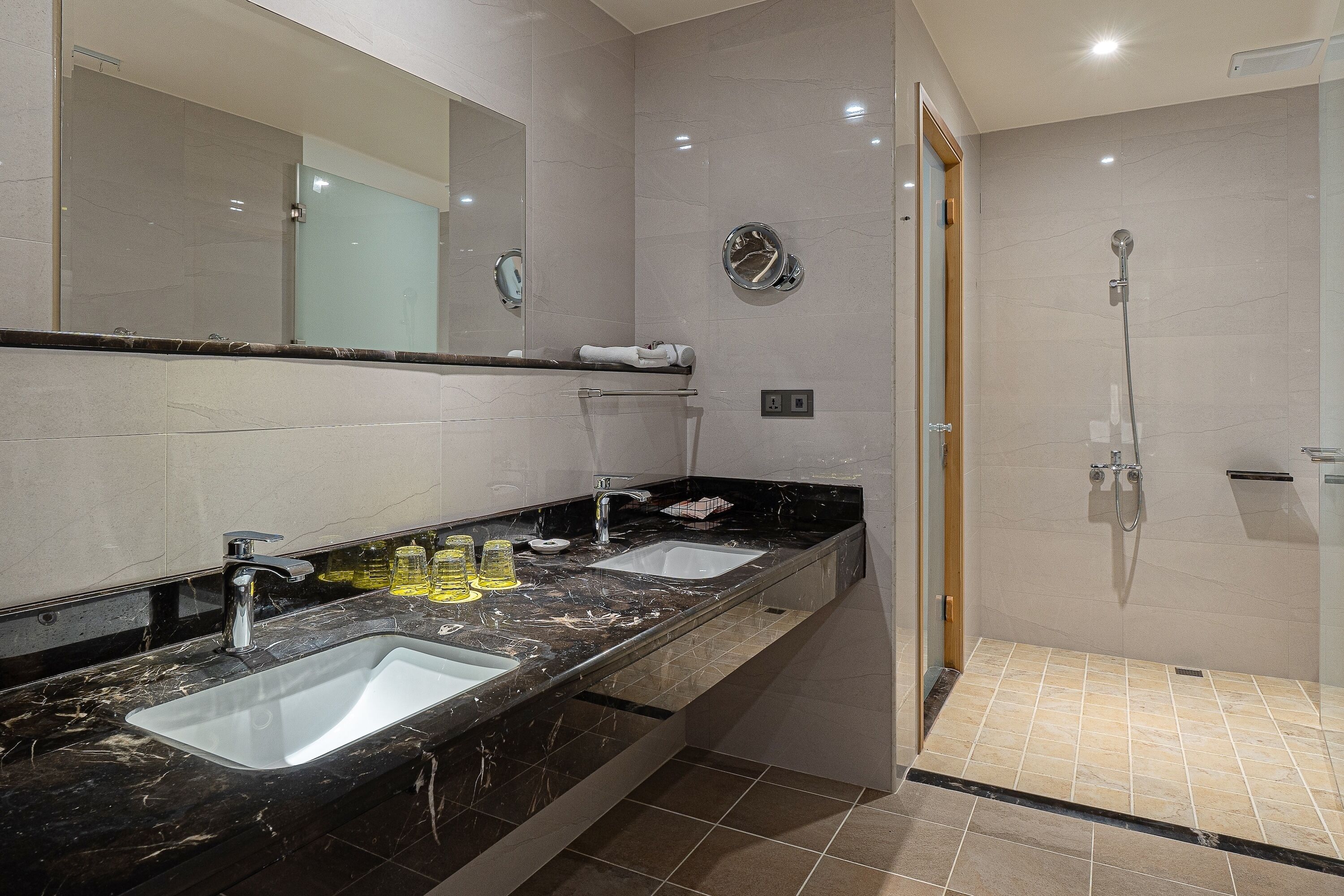 Un baño moderno con dos lavamanos, un espejo grande y una zona de ducha.