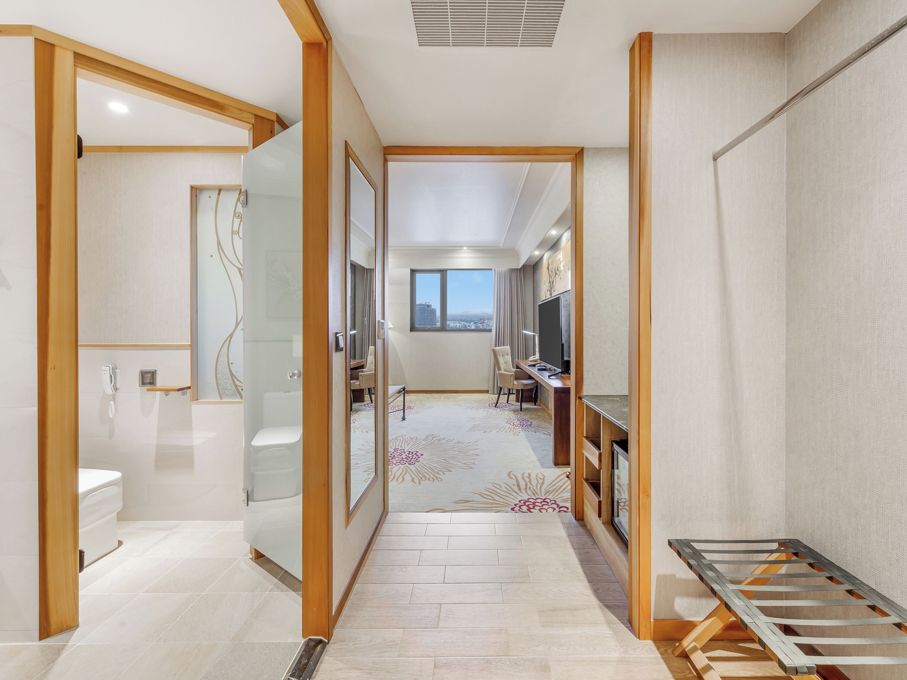 Une chambre d’hôtel avec salle de bain, un bureau avec un ordinateur, une chaise et une vue sur la ville.