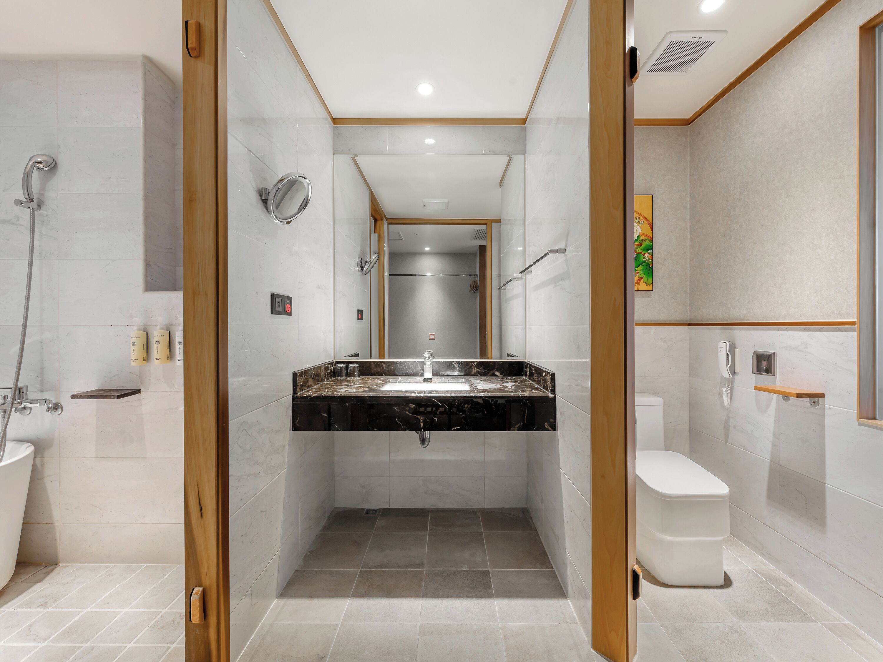 Un baño moderno con lavamanos de mármol, ducha e inodoro.