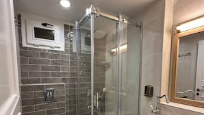 Ein modernes Badezimmer mit einer gläsernen Duschkabine, einer weißen Toilette und einem Becken aus Stein.